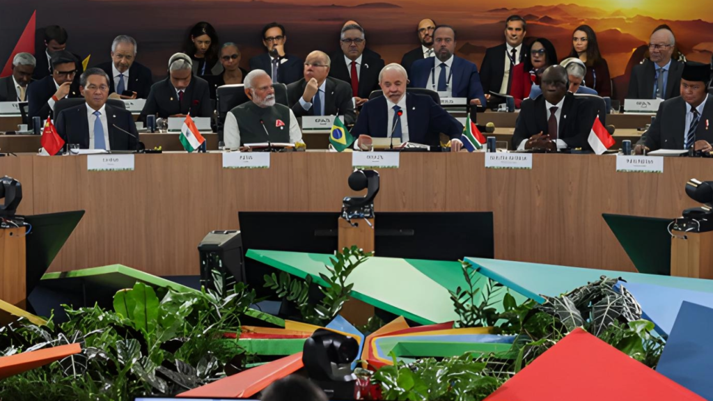BRICS leaders at a conference table with a banner “BRICS Brasil 2025” behind them.