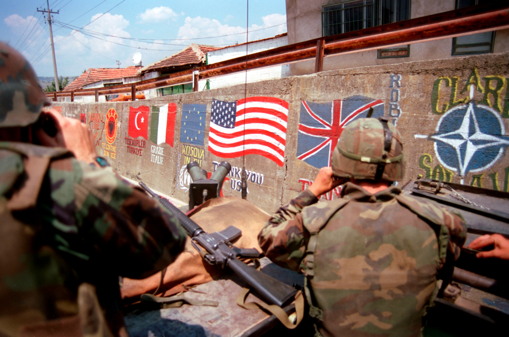 U.S. Marines with a wall of NATO country flags in Kosovo.